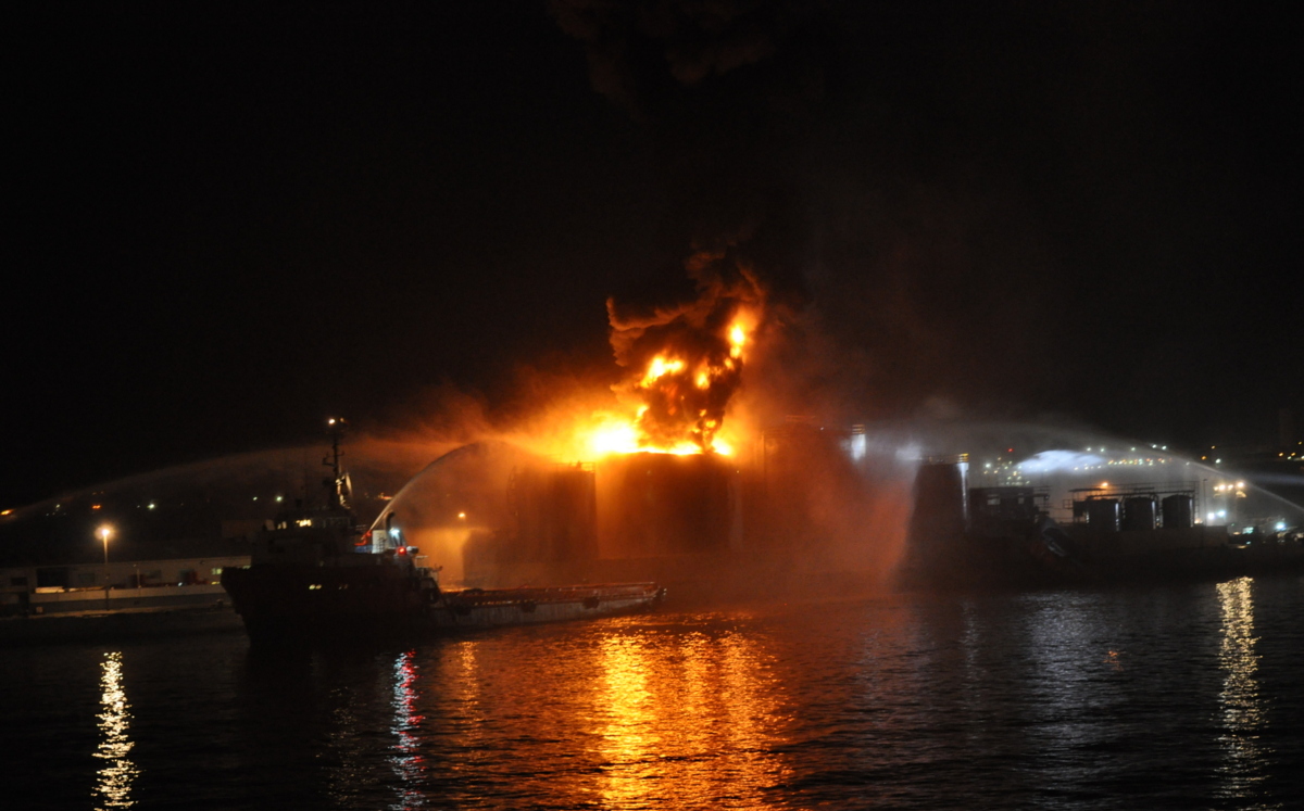 Flames rise from a burning oil tank at night